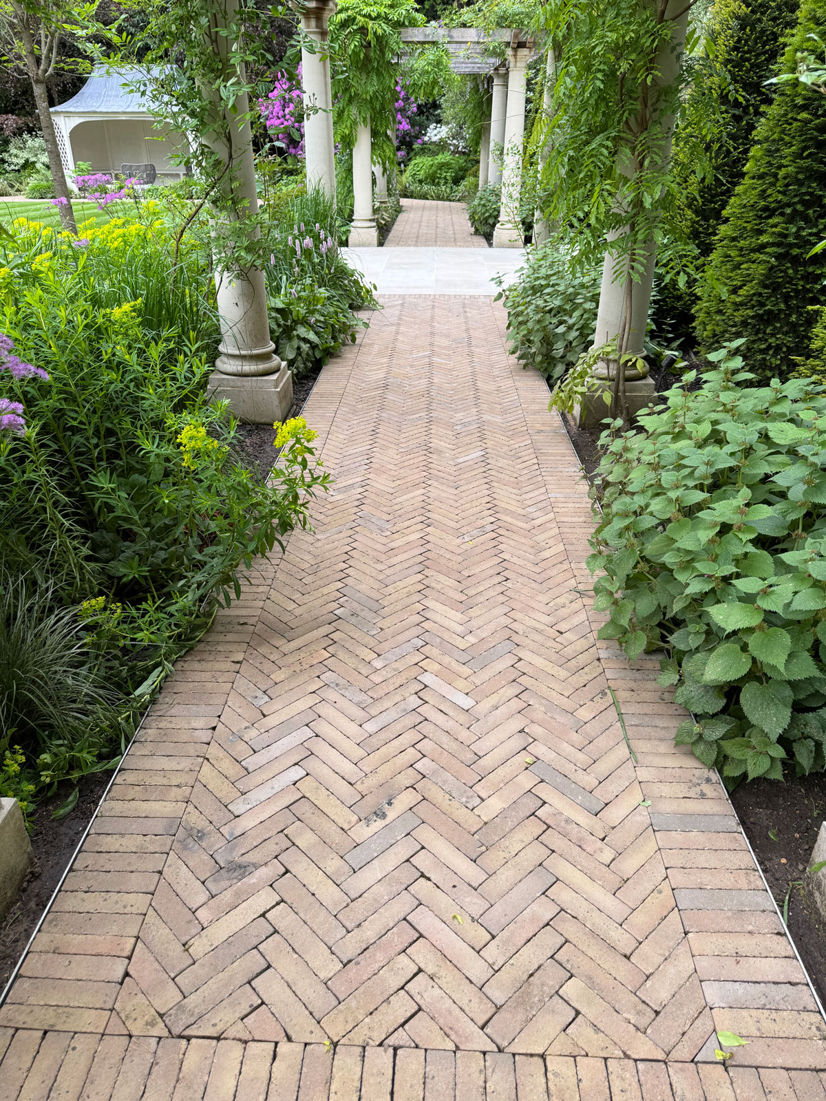 Jet-washed-herringbone-brick-path-between-garden-borders-with-masonry-columns.jpg
